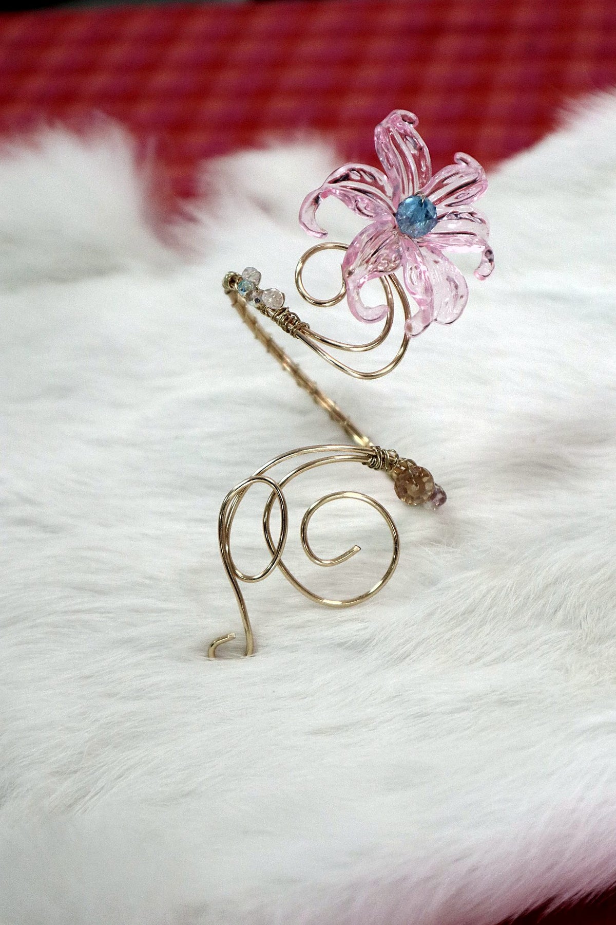 Gold-coloured wire arm cuff with a pink flower and blue bead