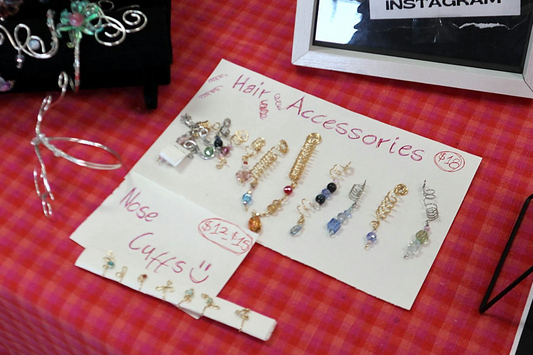 Hand-lettered hair accessories sign with wire hair coils and charms on a table