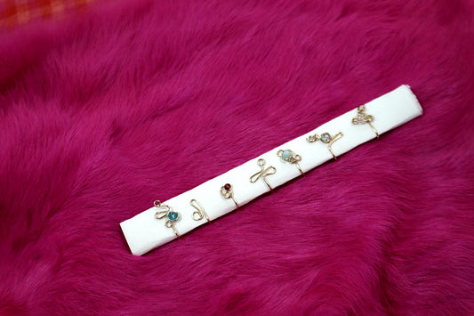 Six wire rings with tiny beads laid on a white card on pink fur